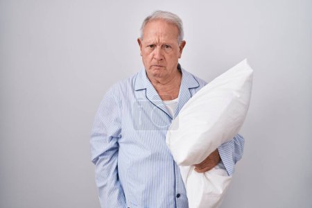 Photo for Senior man with grey hair wearing pijama hugging pillow skeptic and nervous, frowning upset because of problem. negative person. - Royalty Free Image