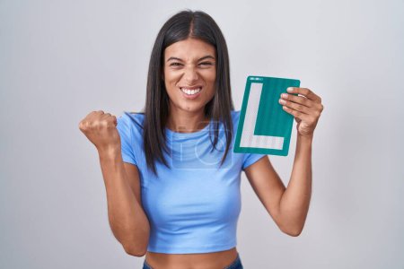 Photo for Brunette young woman holding l sign for new driver screaming proud, celebrating victory and success very excited with raised arms - Royalty Free Image