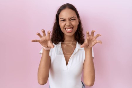 Téléchargez les photos : Jeune femme hispanique portant casual t-shirt blanc souriant drôle faisant griffe geste comme chat, expression agressive et sexy - en image libre de droit