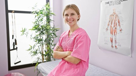 Eine lächelnde Kaukasierin in rosa Peelings steht selbstbewusst in einem Krankenhauszimmer, im Hintergrund ein anatomisches Poster.