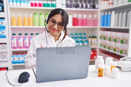 Photo for Young arab woman working at pharmacy drugstore using laptop success sign doing positive gesture with hand, thumbs up smiling and happy. cheerful expression and winner gesture. - Royalty Free Image