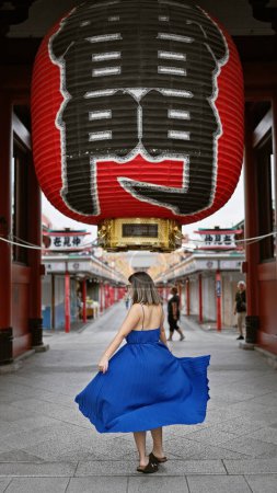 Foto de Mujer hispana efervescente baila alegremente, girando en hermoso vestido en medio de la espléndida arquitectura del templo senso ji en tokyo. recorriendo Japón, ella exuda felicidad en la aventura de vacaciones urbanas. - Imagen libre de derechos