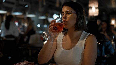 Téléchargez les photos : Jeune belle femme hispanique buvant un verre de vin rouge au restaurant - en image libre de droit
