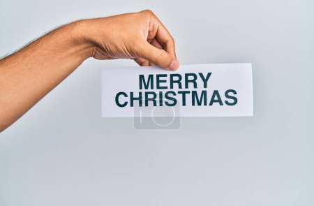 Hand of caucasian man holding paper with merry christmas message over isolated white background