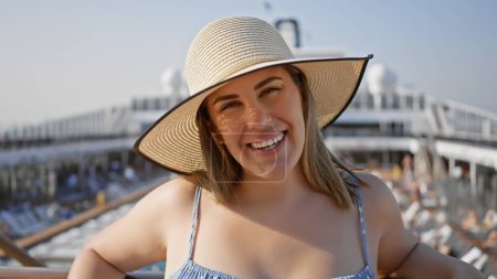 Téléchargez les photos : Une jeune femme latina souriante dans un chapeau de paille sur un pont de bateau de croisière sous un ciel ensoleillé - en image libre de droit