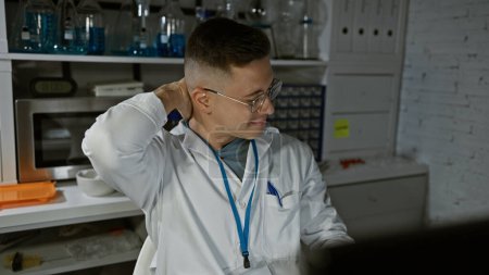 Photo for Young hispanic man in lab coat touching neck indoors at a laboratory setting, exuding professionalism and comfort. - Royalty Free Image