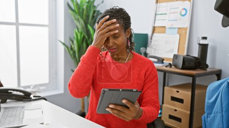 Téléchargez les photos : Afro-américaine femme souligné bureau intérieur technologie tablette professionnel mature - en image libre de droit