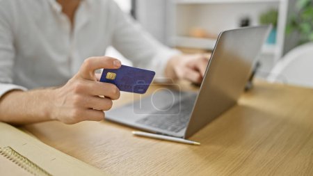 Téléchargez les photos : Main de l'homme d'affaires shopping avec ordinateur portable et carte de crédit au bureau - en image libre de droit