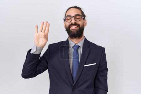Photo for Hispanic man with beard wearing suit and tie showing and pointing up with fingers number four while smiling confident and happy. - Royalty Free Image