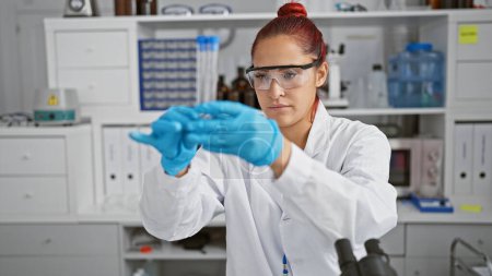 Photo for Captivating portrait, young, beautiful redhead scientist engrossed in meticulous lab work, wielding test tubes with definitive precision inside a state-of-the-art science research center. - Royalty Free Image