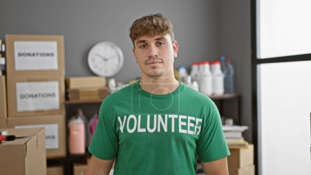 Photo for Handsome young hispanic man volunteers at charity center, his serious face reflecting the gravity of work in community service - Royalty Free Image