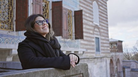 Téléchargez les photos : Une femme souriante avec des lunettes, profitant de sa visite dans un palais de style ottoman à Istanbul. - en image libre de droit
