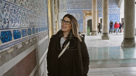 Photo for Smiling woman admires ornate tiles at topkapi palace in istanbul, epitomizing turkish heritage and travel. - Royalty Free Image