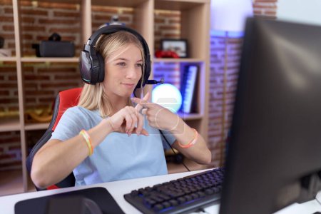 Junge kaukasische Frau spielt Videospiele mit Kopfhörer Ablehnung Ausdruck Daumendrücken tut negatives Zeichen 