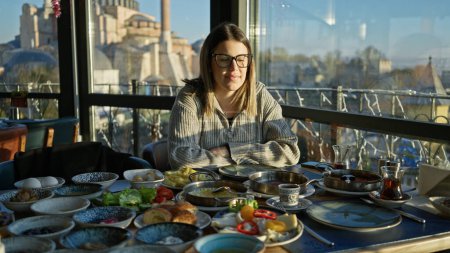 Eine junge Frau frühstückt in einem Restaurant mit Blick auf die Hagia Sophia in Istanbul, Türkei