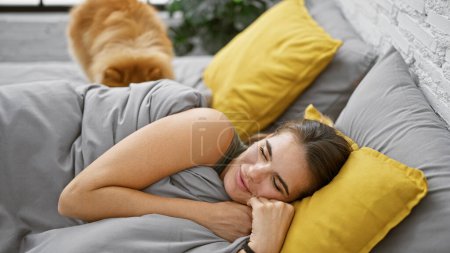 Exhausted but beautiful young hispanic woman sleeping comfortably with her cuddly dog in the cozy relaxation of her indoor apartment bedroom, resting in her pajamas on a comfortable bed