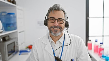 Téléchargez les photos : Jeune homme hispanique aux cheveux gris scientifique portant un casque ayant un appel vidéo au laboratoire - en image libre de droit