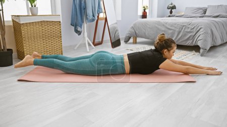 Photo for Young beautiful hispanic woman training lumbar exercise at bedroom - Royalty Free Image