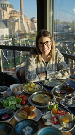Téléchargez les photos : Femme souriante profitant du petit déjeuner avec vue sur hagia sophia dans un restaurant à Istanbul - en image libre de droit