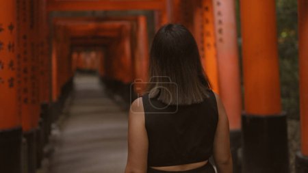 Photo for Beautiful glasses-wearing hispanic woman embracing a casual walk at fushimi's torii gates, kyoto feeling the spirituality of the path - behind yet moving forward - Royalty Free Image