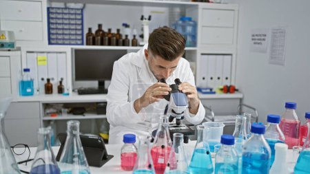 Photo for Passionate young hispanic man engrossed in serious scientific research, fully concentrated, diligently working in the lab with microscope - a fascinating venture into medical biology - Royalty Free Image