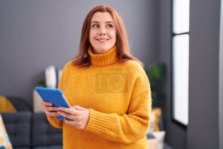 Photo for Young beautiful plus size woman using touchpad standing at home - Royalty Free Image