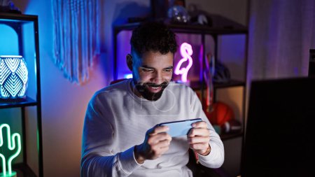 Photo for Happy man gaming on smartphone in a colorful neon-lit room at night - Royalty Free Image
