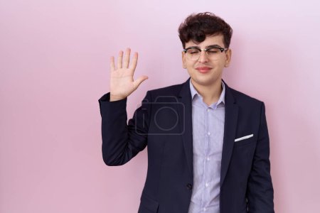 Téléchargez les photos : Jeune homme non binaire avec barbe portant costume et cravate montrant et pointant vers le haut avec les doigts numéro cinq tout en souriant confiant et heureux. - en image libre de droit
