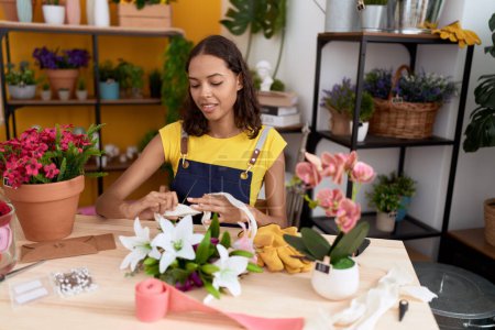 Téléchargez les photos : Young african american woman florist make bouquet of flowers at flower shop - en image libre de droit