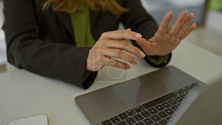 Photo for A professional hispanic woman gesturing during a meeting in a modern office setting - Royalty Free Image