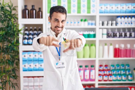 Photo for Handsome hispanic man working at pharmacy drugstore pointing to you and the camera with fingers, smiling positive and cheerful - Royalty Free Image