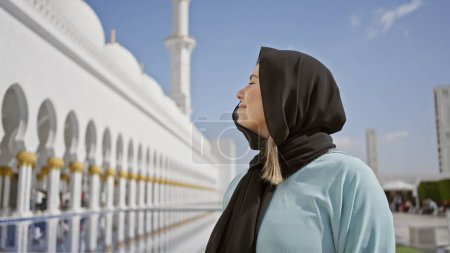 Smiling woman in hijab at abu dhabi mosque exemplifies cultural tourism and islamic architecture.