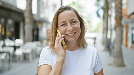 Téléchargez les photos : Jeune femme blonde parlant au téléphone à la rue - en image libre de droit