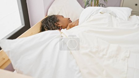 Photo for African woman resting peacefully in a bright bedroom setting, exuding tranquility and maturity. - Royalty Free Image