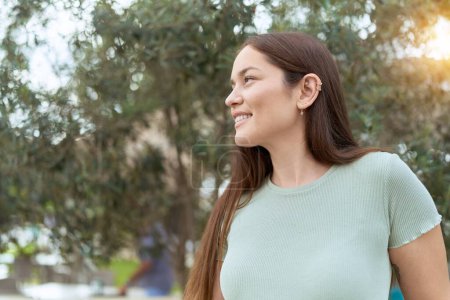 Téléchargez les photos : Jeune belle femme souriante confiante regardant vers le côté au parc - en image libre de droit