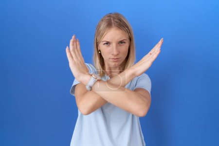 Young caucasian woman wearing casual blue t shirt rejection expression crossing arms doing negative sign, angry face 