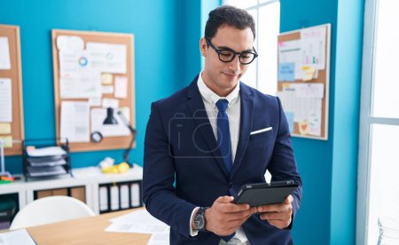 Photo for Young hispanic man business worker smiling confident using touchpad at office - Royalty Free Image