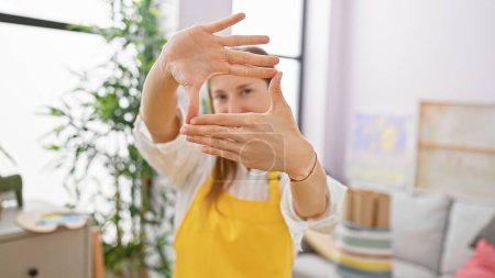 Téléchargez les photos : Une jeune femme artiste encadrant une perspective avec ses mains dans un studio intérieur lumineux. - en image libre de droit