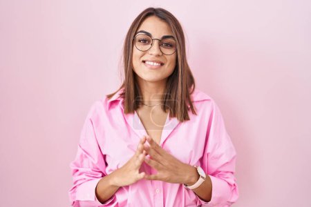 Photo for Young hispanic woman wearing glasses standing over pink background hands together and fingers crossed smiling relaxed and cheerful. success and optimistic - Royalty Free Image