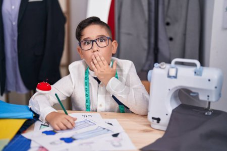 Photo for Young hispanic kid at tailor room covering mouth with hand, shocked and afraid for mistake. surprised expression - Royalty Free Image