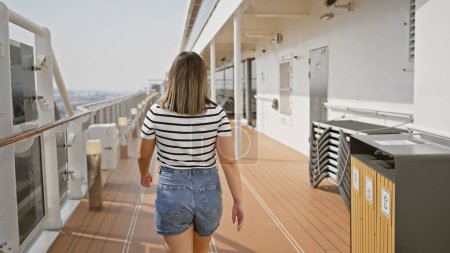A young brunette woman enjoys a leisurely walk on the promenade deck of a cruise ship, symbolizing travel and adventure at sea.
