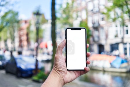 Téléchargez les photos : Homme tenant smartphone montrant écran blanc à Amsterdam - en image libre de droit