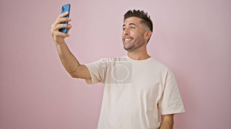 Photo for Confident young hispanic man enjoys lively video call, smiling over his smartphone isolated on a vibrant pink wall background - Royalty Free Image
