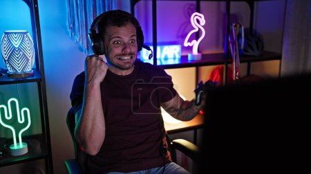 Photo for Hispanic man with beard in dark gaming room enjoying video games at night, showcasing technology and leisure. - Royalty Free Image