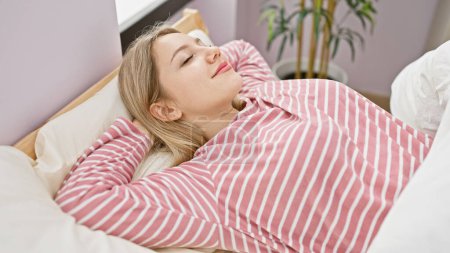 Foto de Una joven tranquila con cabello rubio duerme en un dormitorio luminoso, mostrando descanso, comodidad y un ambiente acogedor en el hogar. - Imagen libre de derechos