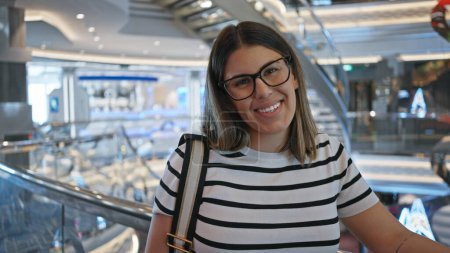 Foto de Una joven sonriente con gafas dentro de un moderno crucero de lujo de vacaciones, exudando elegancia y ocio. - Imagen libre de derechos
