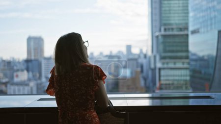 Téléchargez les photos : Belle femme d'affaires hispanique en lunettes, vue imprenable sur le paysage urbain depuis la fenêtre du gratte-ciel dans l'horizon urbain du Japon - en image libre de droit