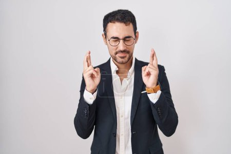 Photo for Handsome business hispanic man standing over white background gesturing finger crossed smiling with hope and eyes closed. luck and superstitious concept. - Royalty Free Image
