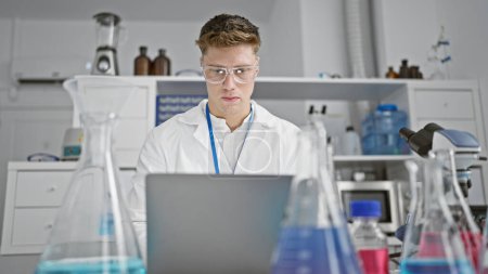Foto de Hombre joven caucásico científico se centró en escribir en el ordenador portátil en el laboratorio - Imagen libre de derechos