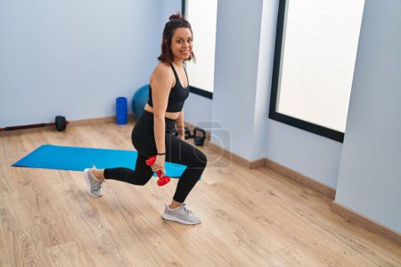 Téléchargez les photos : Jeune belle femme hispanique souriant entraînement confiant jambes exercice au centre sportif - en image libre de droit